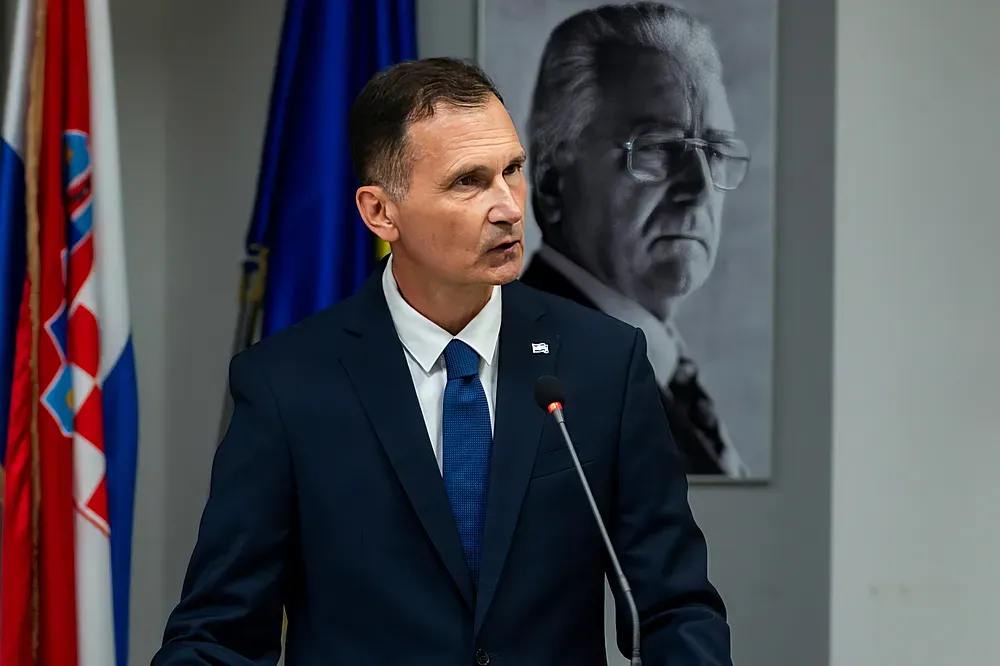Mögötte az elődje, Dragan Primorac jobboldali elnökjelölt az államalapító, Franjo Tuđman fotója előtt
