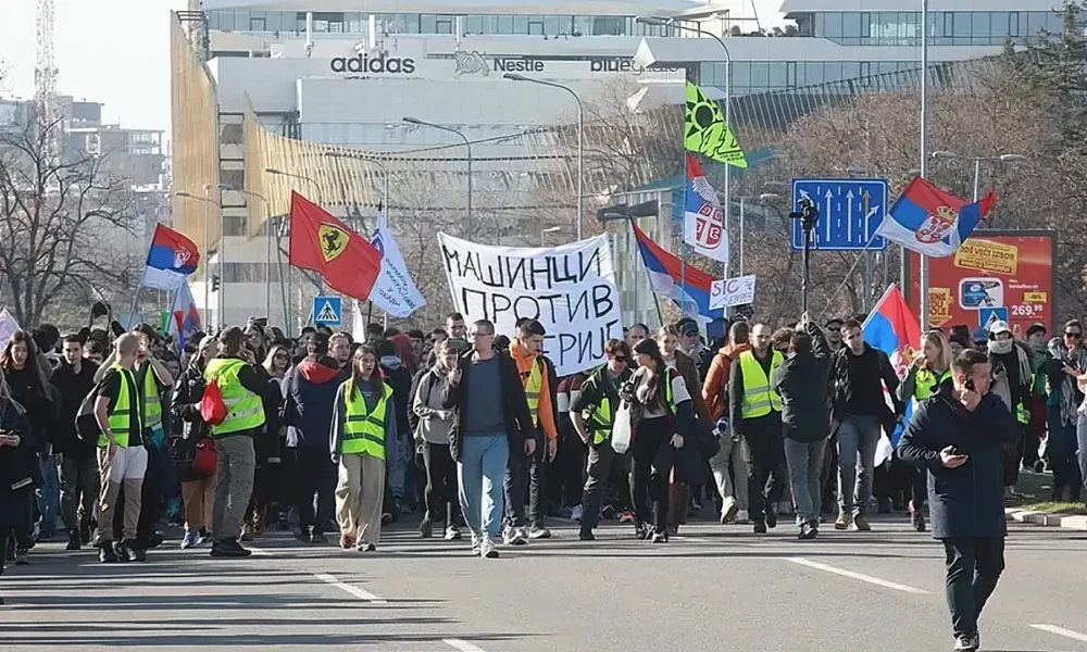 A belgrádi diákok Újvidékre mennek, a felvonulásokat általában a gépészek vezetik, őket könnyű felismerni a "Gépészek a gépezet ellen" feliratú transzparensükről. Ezúttal feltűnik a Ferrari-zászló is, amely az 1996-os nagy diáklázadásra emlékeztet. Az 1996-os és 1997-es nagy belgrádi diáktüntetéseken az egyetemisták hónapokon át tiltakoztak Slobodan Milošević rezsimje ellen
