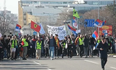 A belgrádi diákok Újvidékre mennek, a felvonulásokat általában a gépészek vezetik, őket könnyű felismerni a "Gépészek a gépezet ellen" feliratú transzparensükről. Ezúttal feltűnik a Ferrari-zászló is, amely az 1996-os nagy diáklázadásra emlékeztet. Az 1996-os és 1997-es nagy belgrádi diáktüntetéseken az egyetemisták hónapokon át tiltakoztak Slobodan Milošević rezsimje ellen