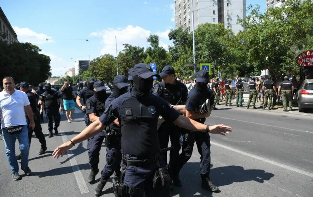 A szerb rezsim tagjai azt állítják, hogy a rendőrök nem őket védik, hanem az államot. Nagy igyekezetükben  az álarcos rendőrök (vagy verőlegények) egy tüntetőt hurcolnak el, akinek csak a lábfeje látszik a "szélsőjobbos" rendőr kezében