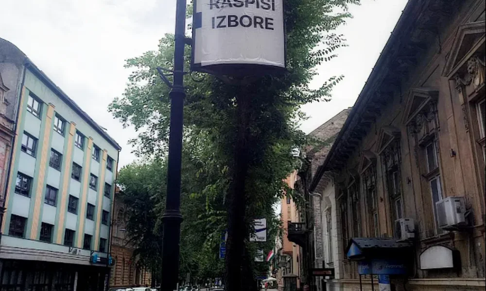 Vajdasági Magyar Plénum, Pásztor Bálint - Szabadkai városkép egy átragasztott plakáttal, amelyen az olvasható, hogy "írd ki a választásokat". A szerb elnök egy kijelentése szerint tisztogatásra készül a nagyobb városokban, és ezzel kapcsolatban alig félreérthetően Szabadkát is megemlítette