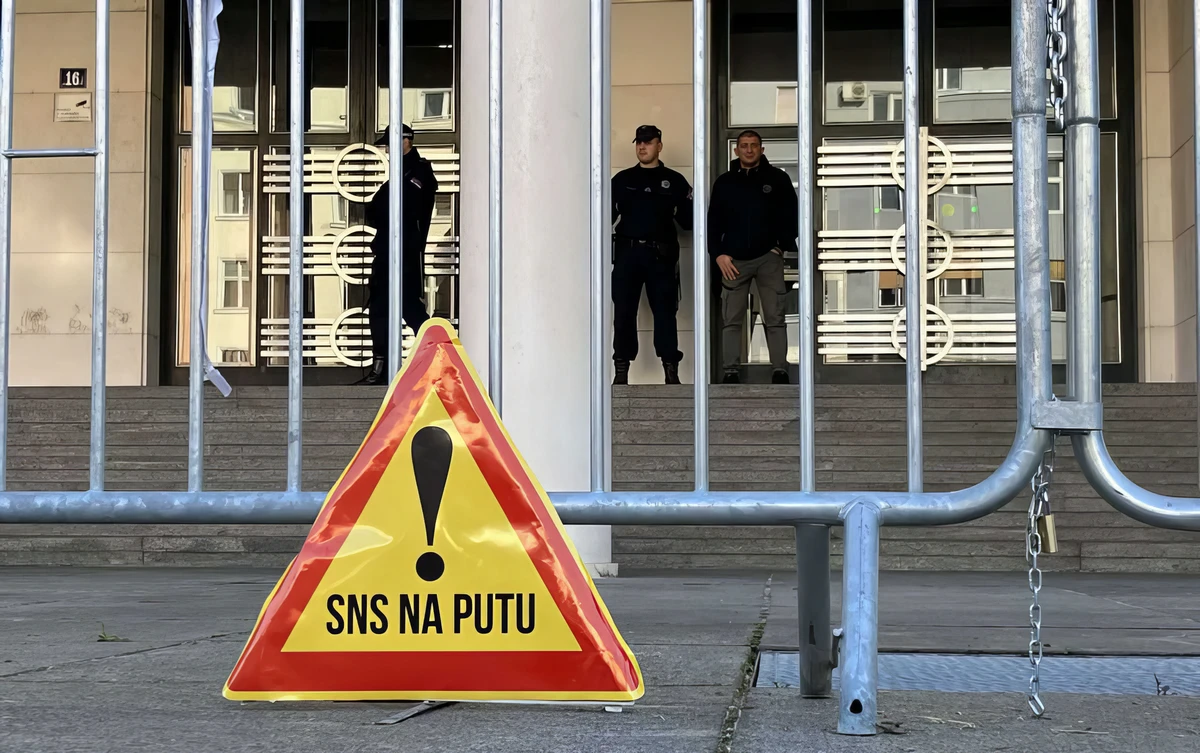 Veszélyt jelző tábla az újvidéki parlament előtt: vigyázat, SNS (Szerb Haladó Párt) az úton, jól megy egy közlekedési vállalkozó sztrájkjához