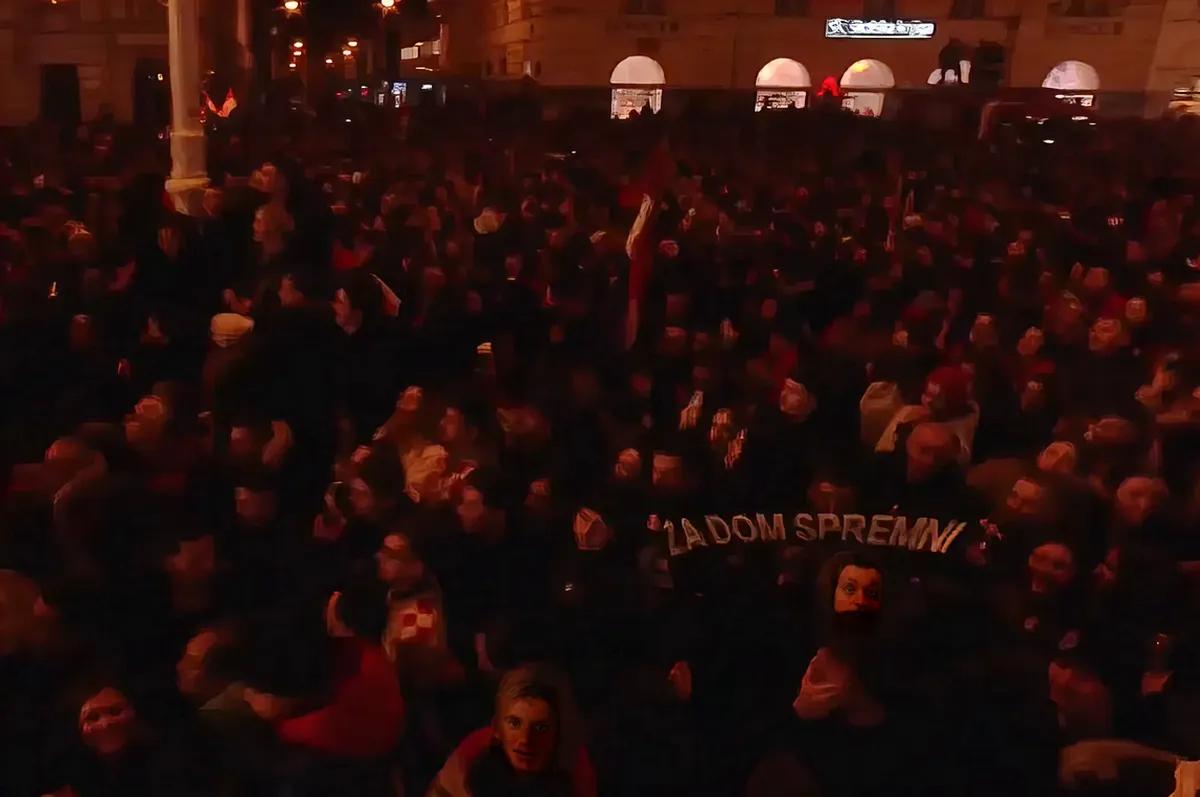 Belgrád is megszólalt a zágrábi kézilabda-válogatott fogadtatása után 2 A "Za dom spremni" felirat egy sálon volt látható a tömegben, de volt HOS-zászló is. A HOS a nacionalista Horvát Jogpárthoz kötődő önkéntes, félkatonai alakulat volt 1991 és 1993 között. Tagjai között voltak horvát nacionalisták, külföldi önkéntesek, valamint szélsőjobboldali szimpatizánsok is. 1993-ban a horvát állam beolvasztotta őket a reguláris hadseregbe, mert túl önállóak és politikailag kényelmetlenek voltak. (Forrás: Screenshot, HRT2)