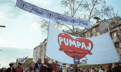 Pumpálnak a helyhatósági választások előtt Kúlán a diákokat támogató emberek, fejük felett a kifeszített transzparens hirdeti a szerb elnök listáját